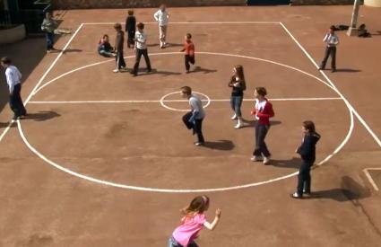 Terrain de sport en terre battue dans une cour d'école.